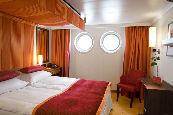 A cabin of category A on board the A-ROSA LUNA and A-ROSA STELLA. Furnished in warm colors with a double bed and portholes as windows.