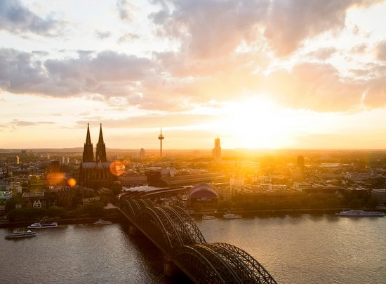 Panoramic view of the city of Cologne with the Cologne Cathedral at sunset. In the foreground, the Hohenzollern Bridge, which crosses the Rhine.