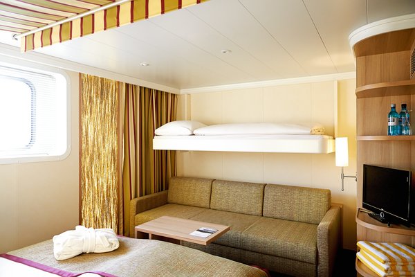 A category G cabin on the A-ROSA FLORA with a double bed, sofa bed, and Pullman bed, as well as a window and a television.