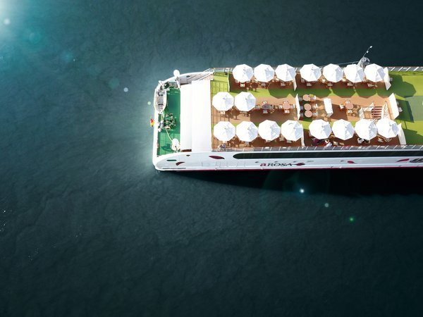 Top view of the sun deck of the river cruise ship A-ROSA with white sun umbrellas and tables on the water.