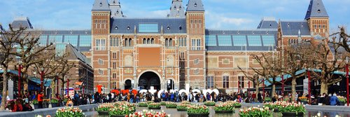 Rijksmuseum in Amsterdam mit Wasserbecken und schwimmenden Blumenarrangements im Vordergrund, Menschen vor dem Museum