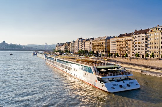River cruise ship on the bank of the Danube in Budapest with historic buildings and the Chain Bridge in the background