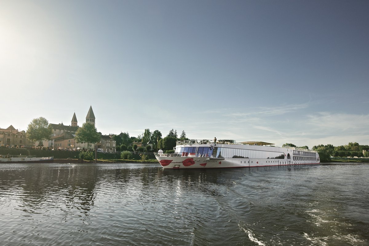 The A-ROSA STELLA is sailing on a calm river in front of a city with historic buildings and two church towers under a clear sky.