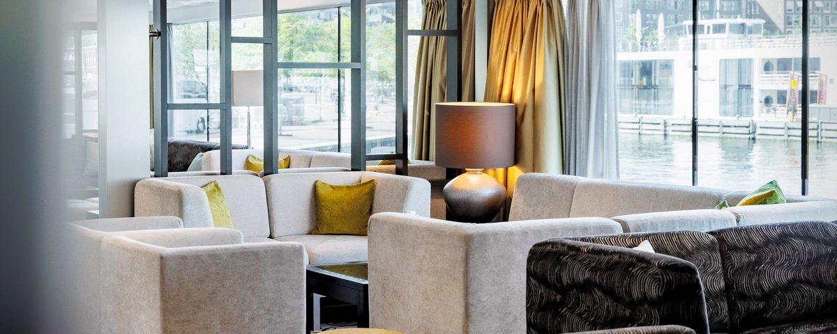 The stylishly furnished panoramic lounge of the A-ROSA CLEA with large floor-to-ceiling windows, modern seating, and a view of the river.