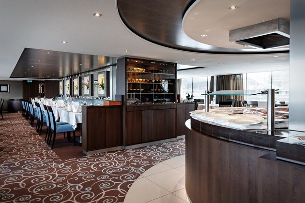 Stylishly set restaurant and buffet area of the A-ROSA CLEA with windows, floral decorations, and dimmed lighting.