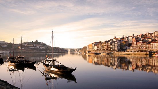 Blick auf die historische Altstadt von Porto mit bunten Häusern am Fluss Douro, im Hintergrund die ikonische Brücke Dom Luís I.