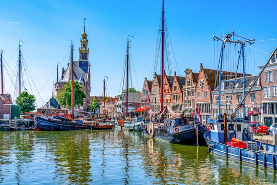 Historische Gebäude und Boote im Hafen von Hoorn, Niederlande, bei blauem Himmel